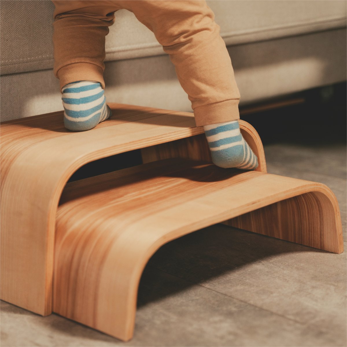 1. Child stepping on wooden step stool with striped socks in a cozy indoor setting
