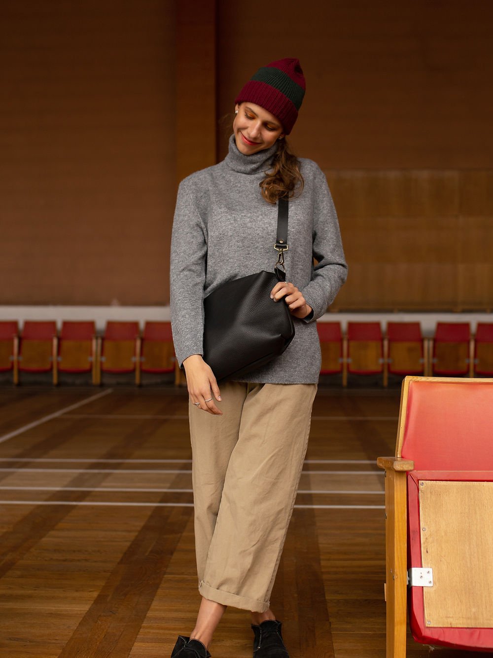1. Woman wearing TOKS VISOKS ROBIN large black leather handbag with adjustable strap, styled with casual outfit in lifestyle setting