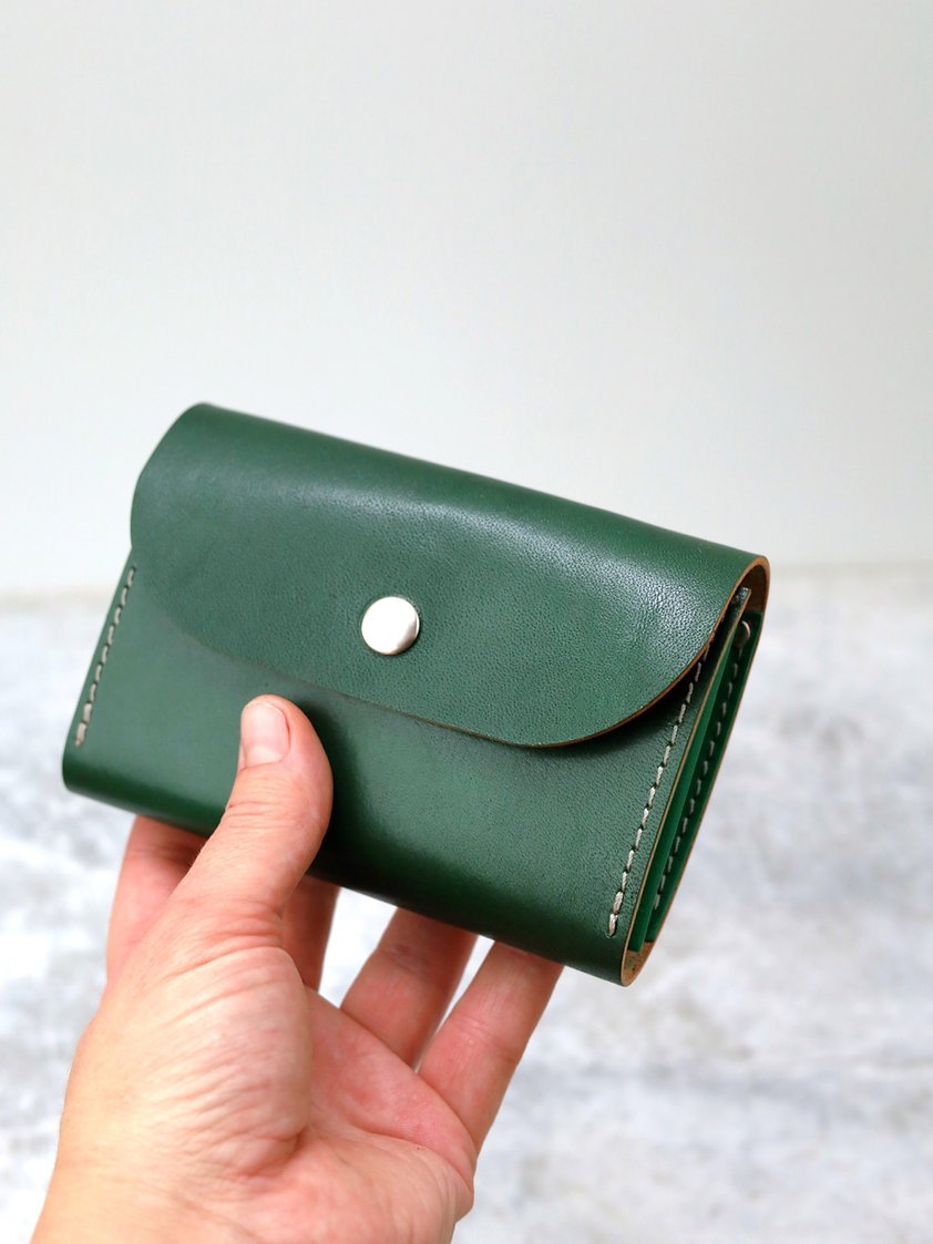 1. Hand holding the FRIDAY Wallet in vibrant green recycled leather by TOKS VISOKS, showcasing its compact design