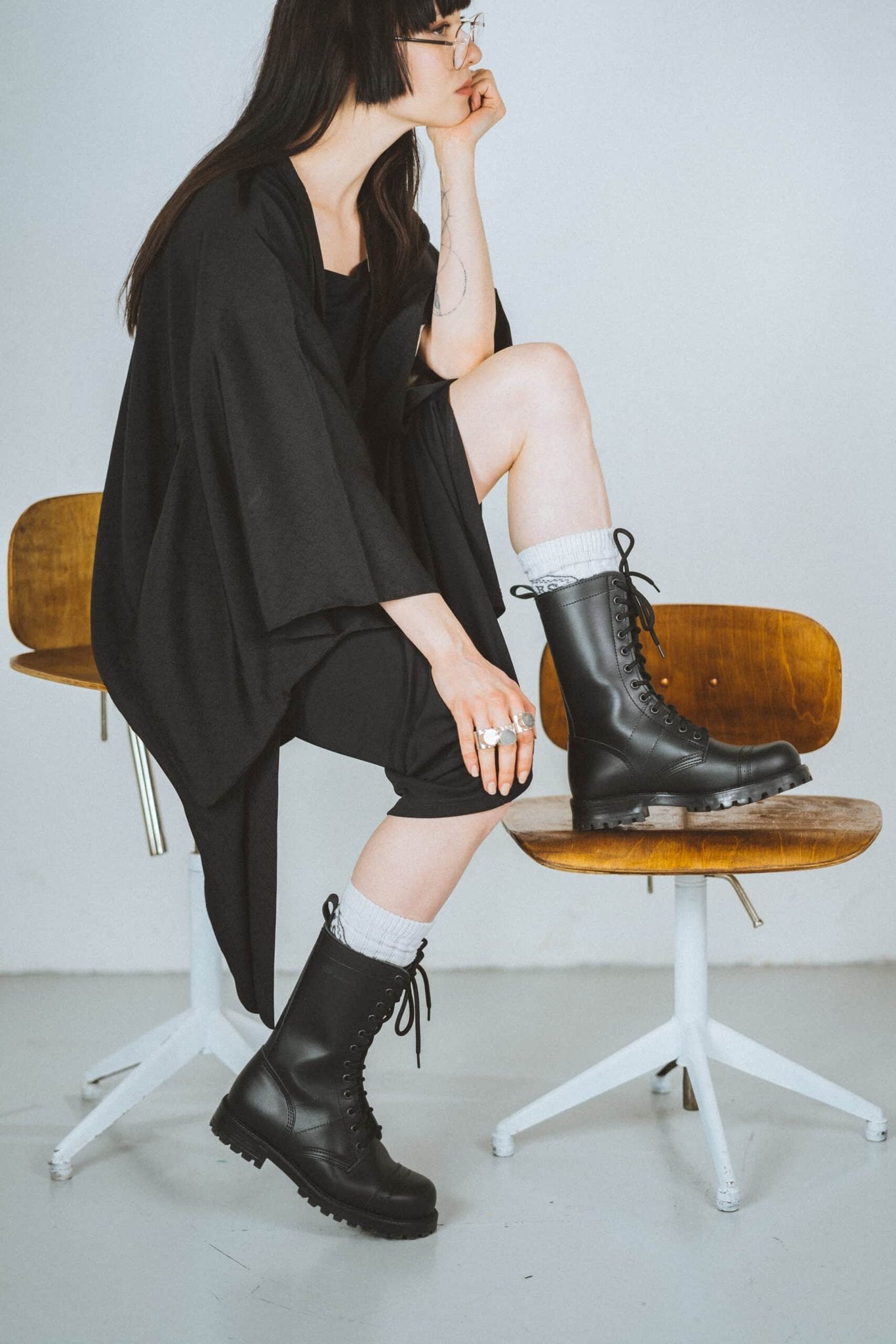 1. Woman wearing Samelin 516 High Aviator Boots in black, styled with casual outfit, seated on chair