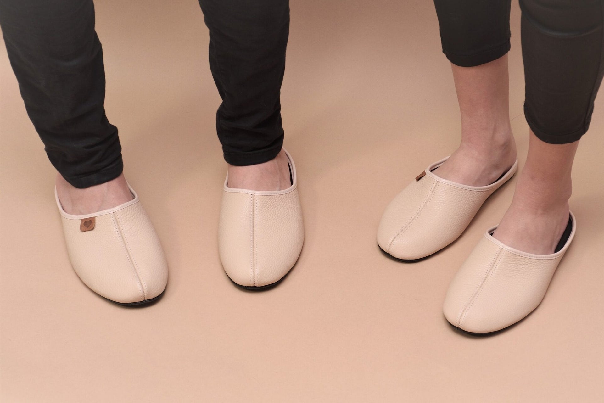 1. Unisex beige leather slippers Sänna by Omaking worn by male and female models, showcasing comfort and style