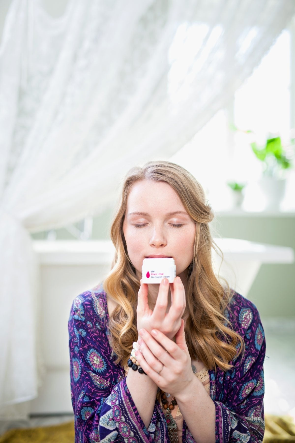 1. Woman enjoying the scent of Tilk! Love Me Moisturising Hand Cream in a serene setting