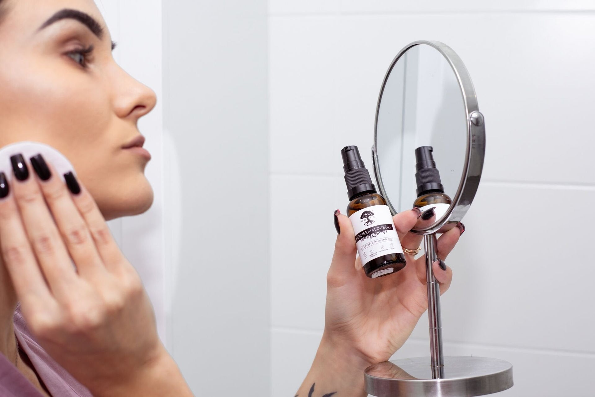 1. Woman using HOIA homespa organic make-up removing oil with cotton pad in front of mirror