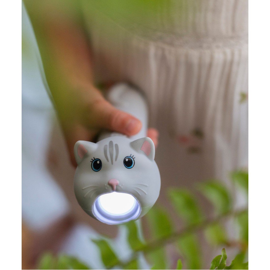 1. Child holding cat-shaped flashlight in garden setting, illuminating path
