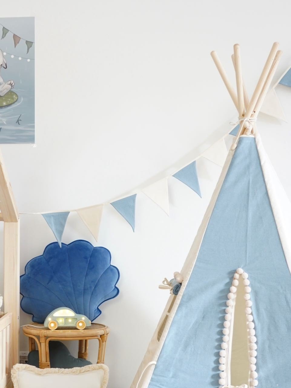 1. Child's room with blue and white teepee tent, shell-shaped cushion, and blue and white garland hanging on the wall