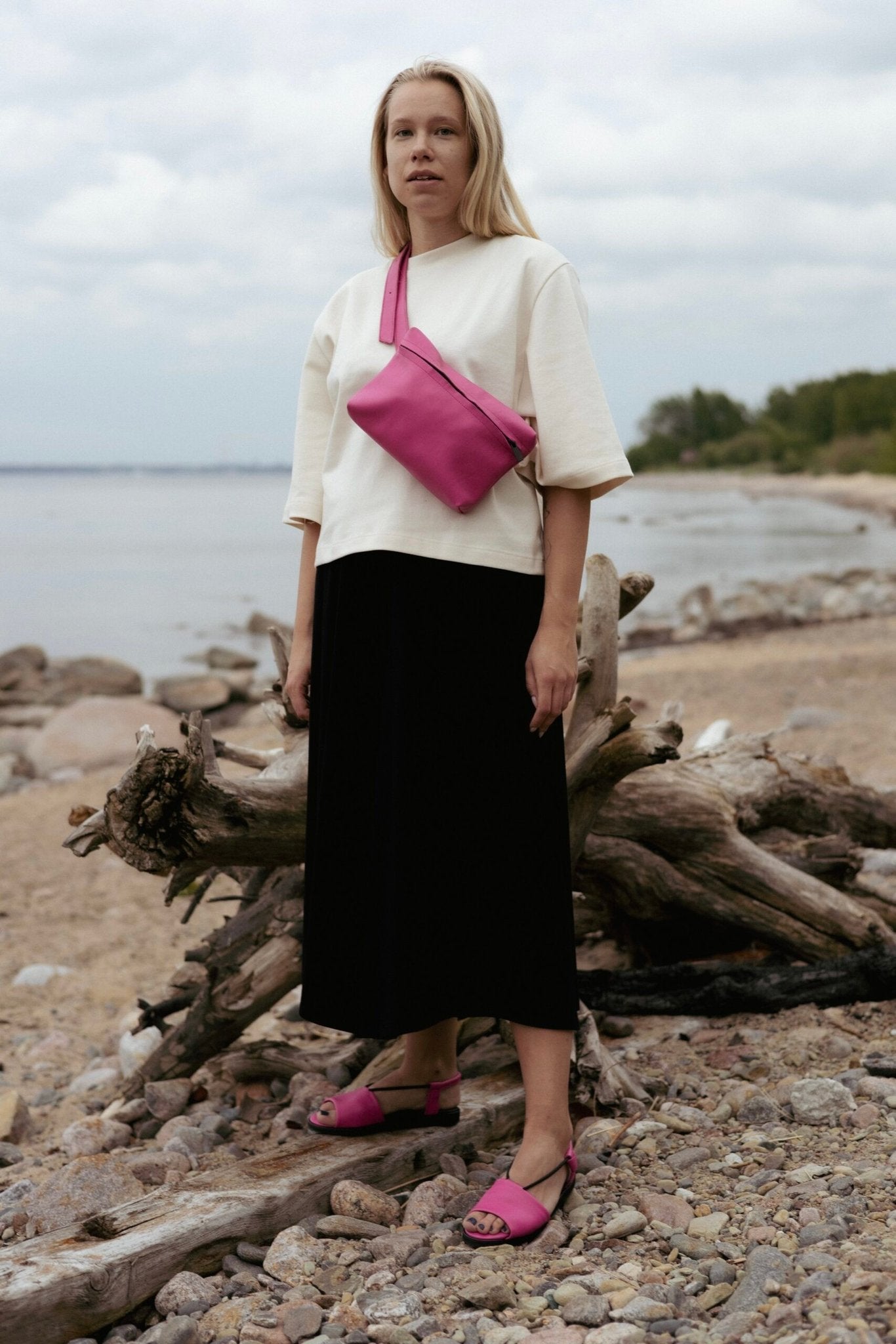 1. Woman wearing Omaking TOKU Lisbon pink leather bag across her shoulder on a beach