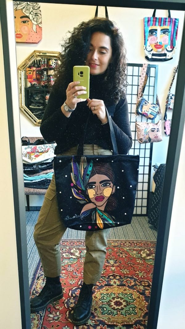 3. Woman taking a mirror selfie with Garbanota HANDBAG LILY - COLORED, showcasing vibrant artwork