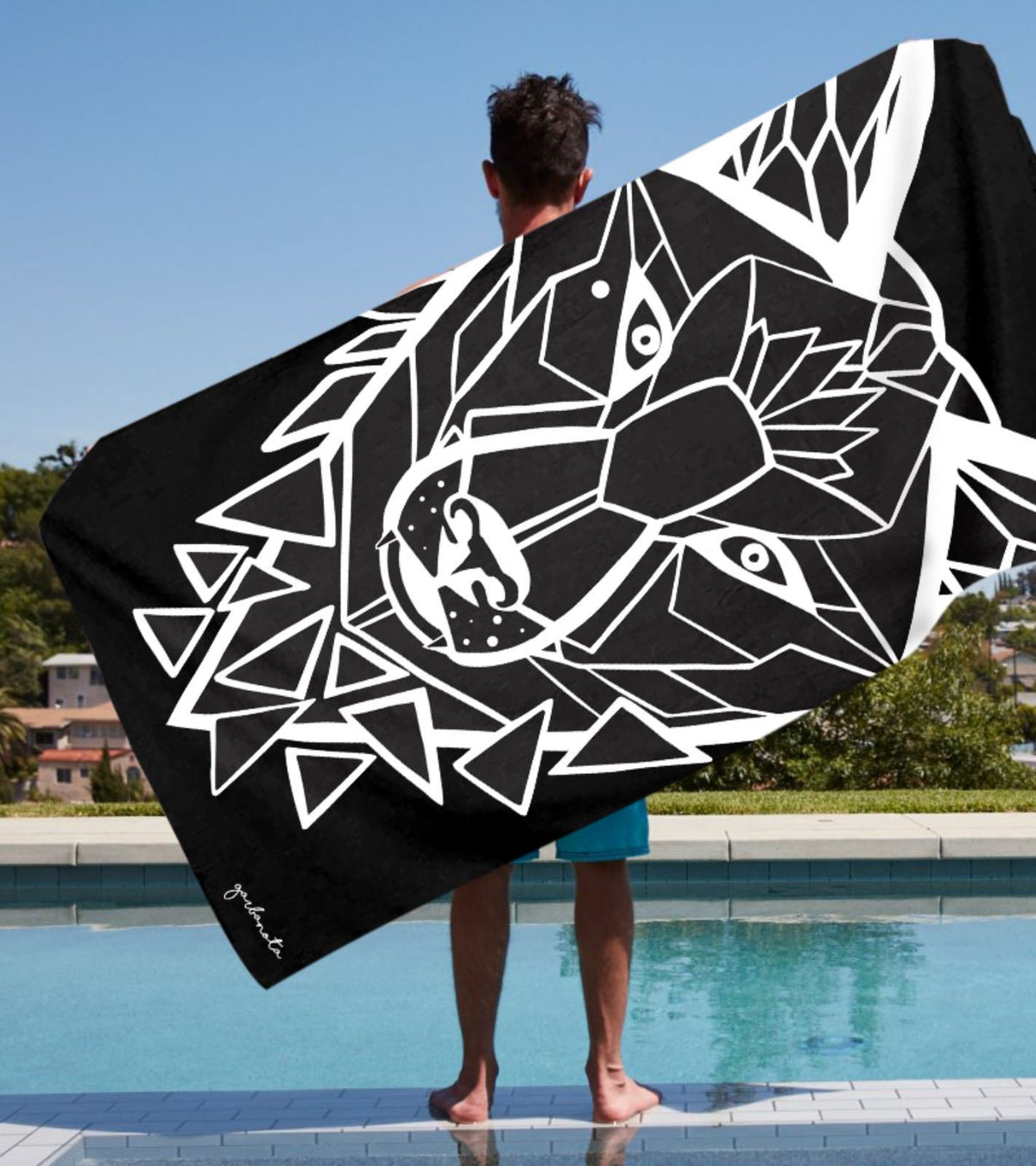 1. Man holding Garbanota Towel White Wolf in black by poolside, showcasing hand-drawn wolf design