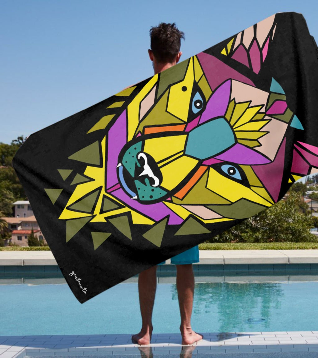 1. Man holding Garbanota Towel Colored Wolf in black with vibrant geometric wolf design by poolside