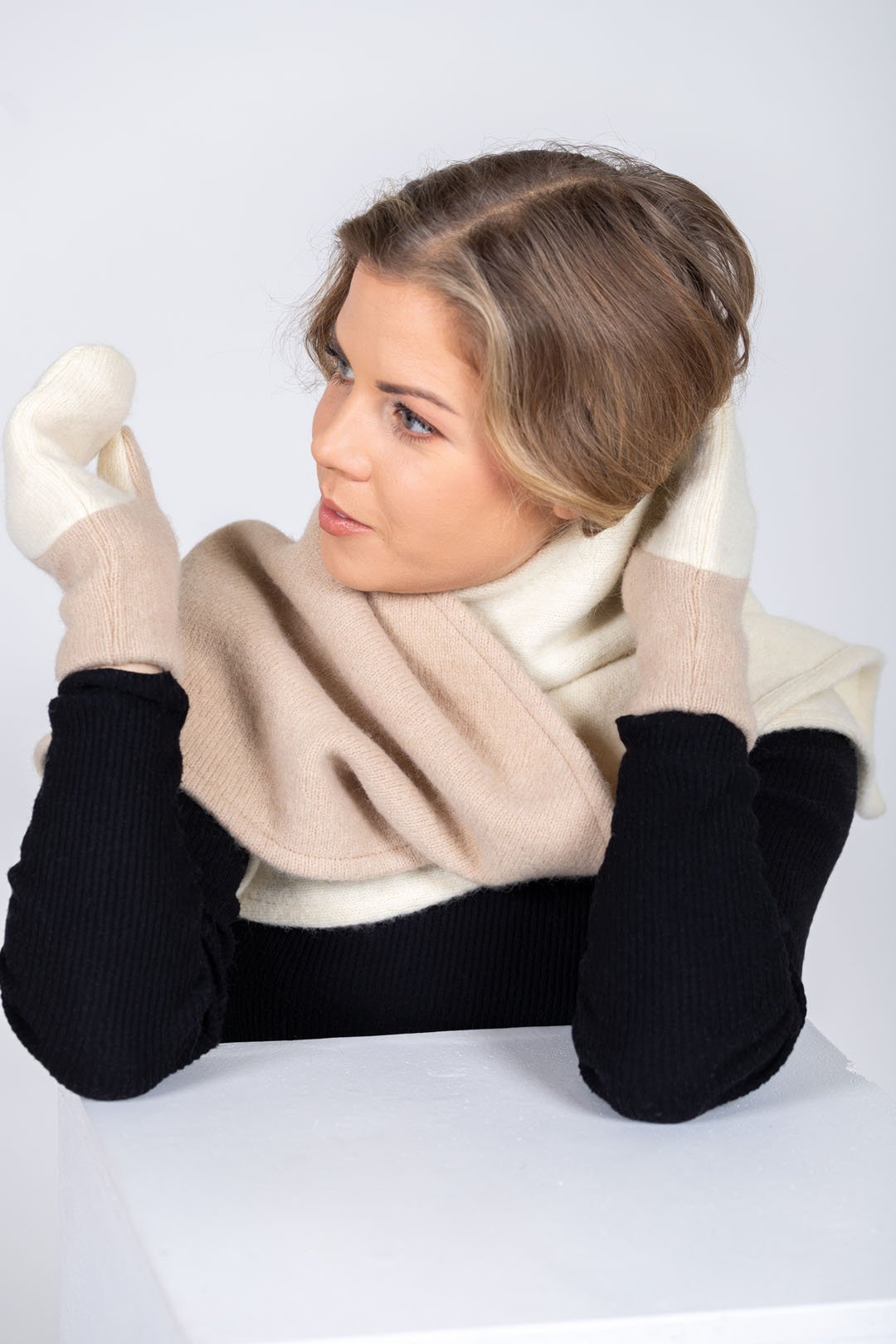 2. Women's HERTTA wool triangle shawl in white and beige, worn as a scarf in a studio setting