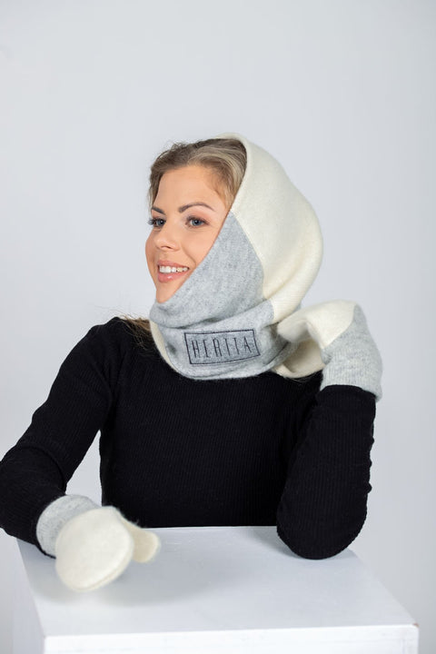 1. Women's versatile handmade wool triangle shawl in white and lightest grey by HERTTA, styled as a hood in studio setting