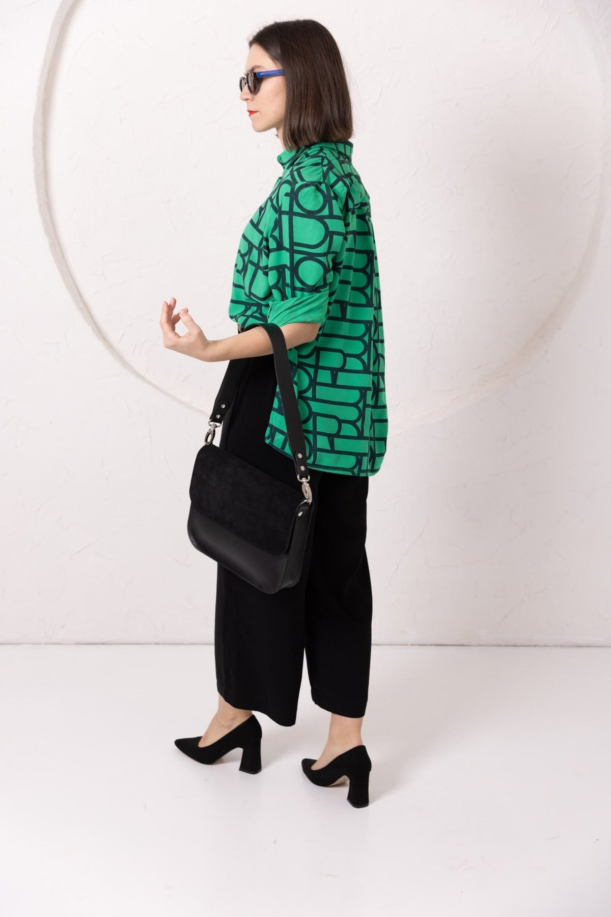 6. Woman in studio with TOKS VISOKS ASTORIA black suede handbag, styled with green top and black pants