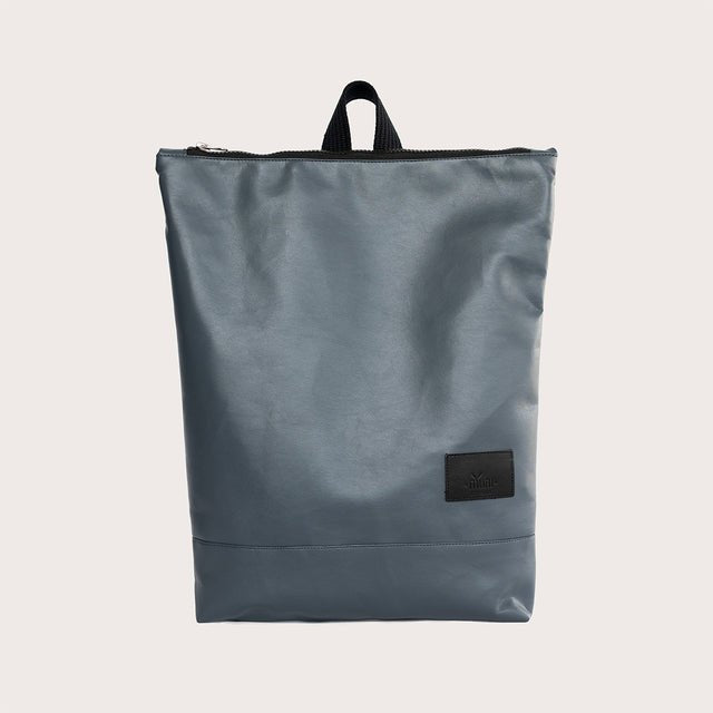 2. Woman carrying Muni faux leather grey backpack in studio, side view