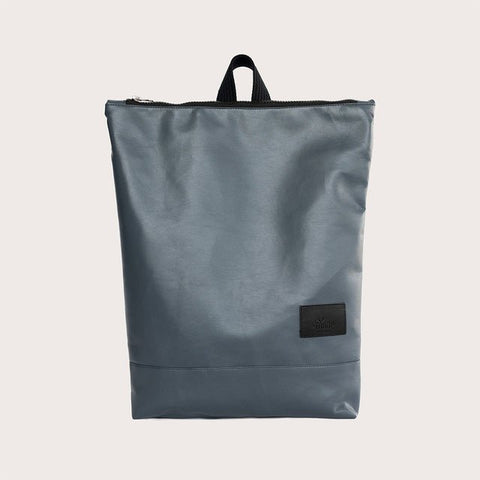 2. Woman carrying Muni faux leather grey backpack in studio, side view