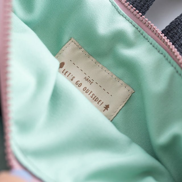 9. Close-up of Muni kids mint bow backpack interior label with 'Let's Go Outside!' text