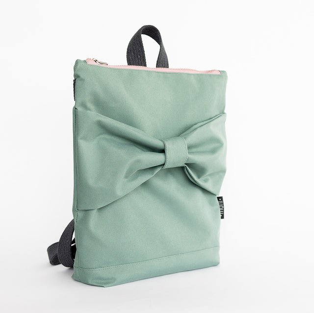 5. Side view of Muni kids mint bow backpack in studio, highlighting bow detail and pink zipper