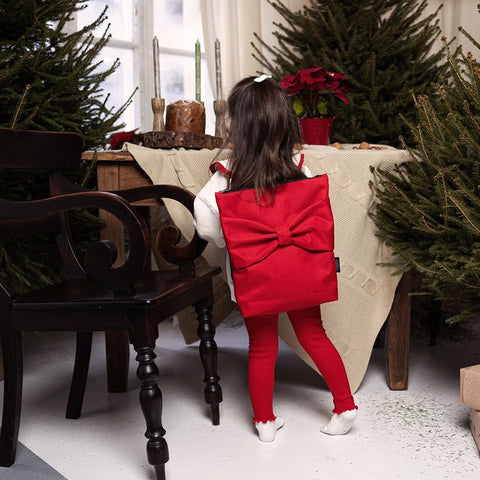 1. Child wearing Muni red bow kids backpack in festive setting