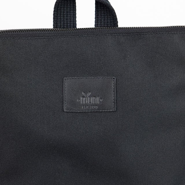 5. Close-up of Muni logo on black waterproof backpack fabric