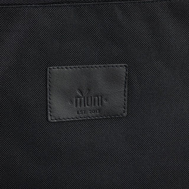 8. Close-up of Muni brand logo on black waterproof polyester fabric