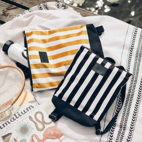 5. Muni striped mustard and white backpack next to a black and white striped backpack