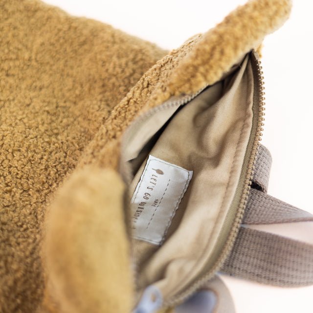 6. Interior view of Muni brown teddy backpack, showing beige lining and zipper closure