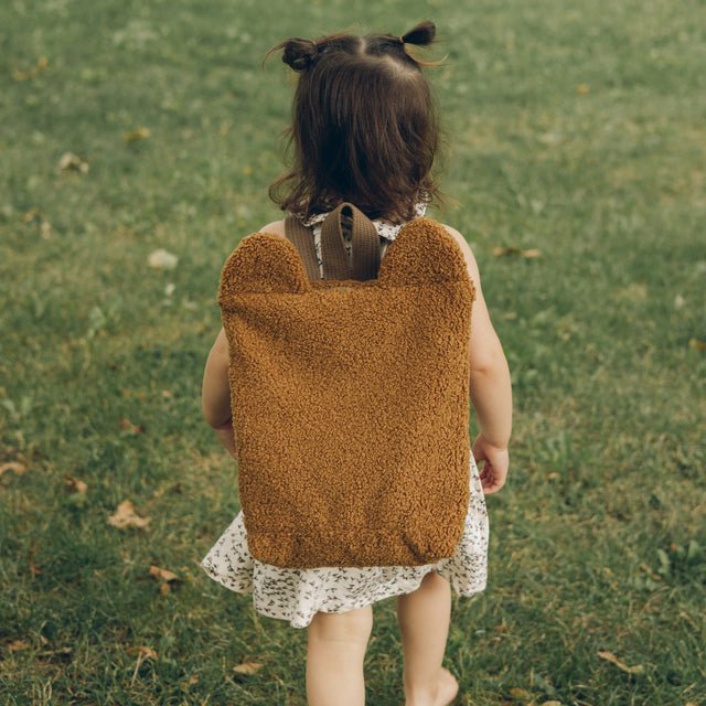 2. Toddler walking with Muni brown teddy backpack in park, highlighting eco-friendly material and cute bear ears