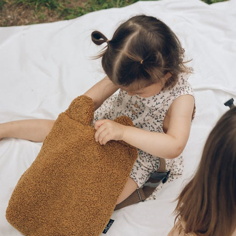 3. Child sitting with Muni brown teddy backpack, showcasing soft texture and playful design