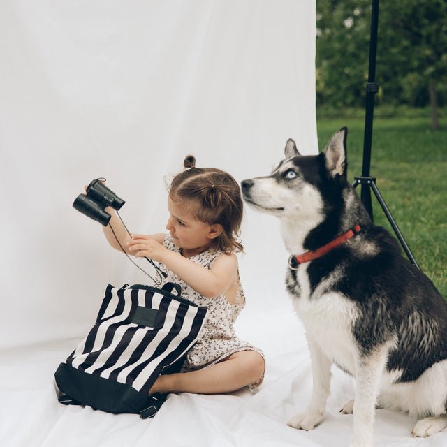 2. Child with Muni black and white striped backpack and dog in outdoor setting