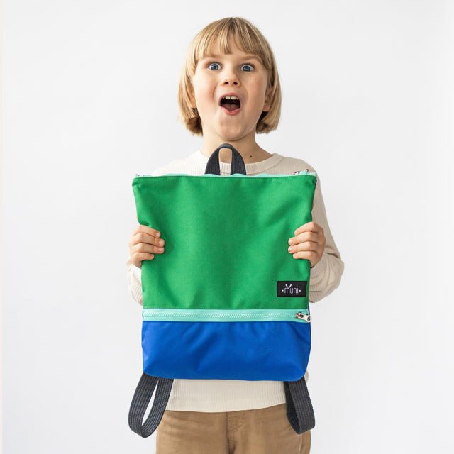 2. Excited child displaying Muni waterproof kids backpack in green and blue, front view