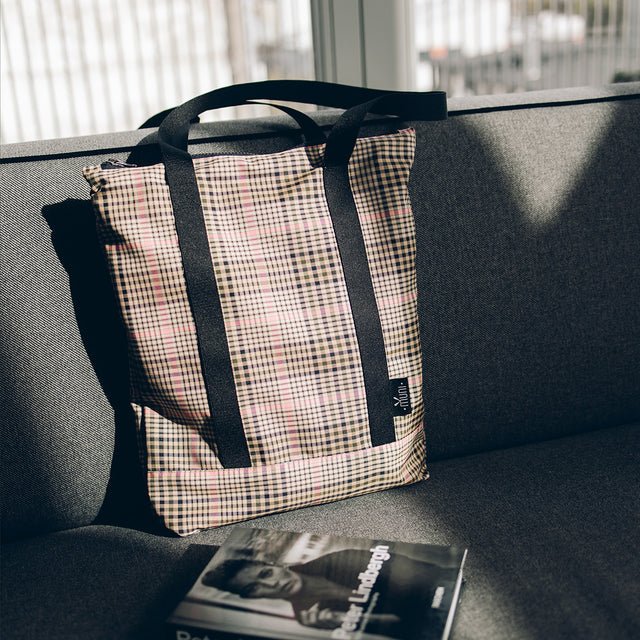 4. Muni tartan tote bag on a grey sofa, showcasing stylish design and practicality in natural light