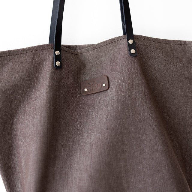 6. Close-up of Muni brown denim tote bag showing brand logo and black leather handles