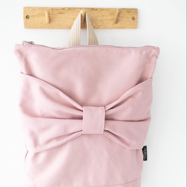 9. Close-up of Muni Pink Bow backpack on hook, highlighting bow detail
