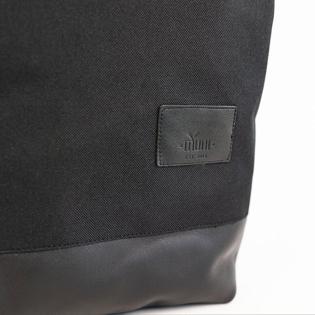 6. Close-up of Muni logo on black leather bottom of waterproof backpack, highlighting brand detail