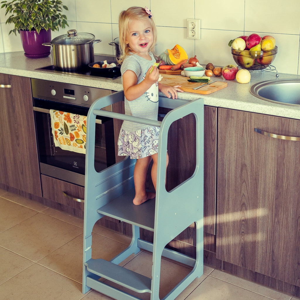 4. Child on blue Montessori helper tower step stool in kitchen with fruit