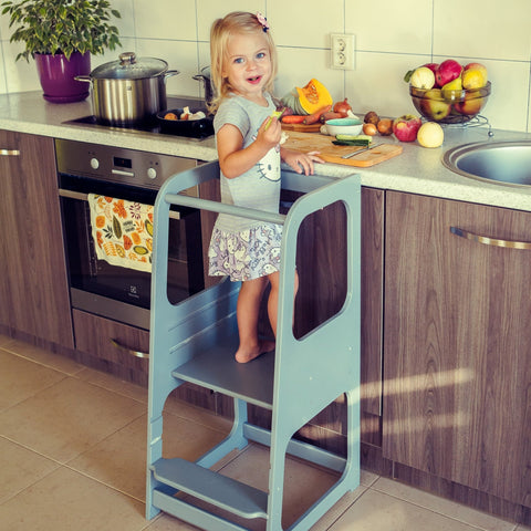 4. Child on blue Montessori helper tower step stool in kitchen with fruit