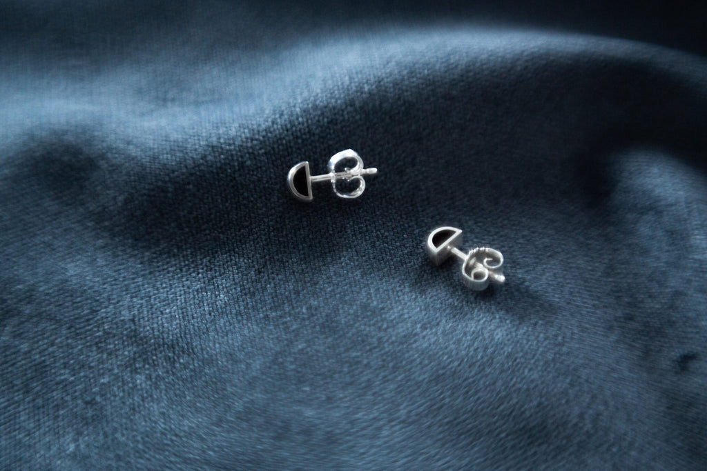 3. Close-up of Maarja Palu HOLLOW small stud earrings on dark fabric, highlighting polished silver and minimalist design