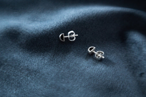 3. Close-up of Maarja Palu HOLLOW small stud earrings on dark fabric, highlighting polished silver and minimalist design