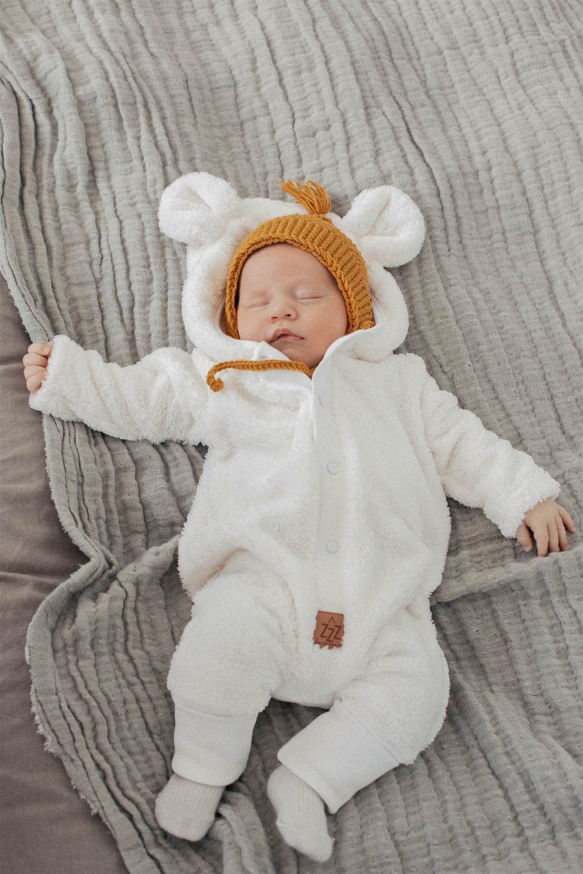 1. Baby sleeping in fuzzy ecru jumpsuit with bear ears hood on grey blanket