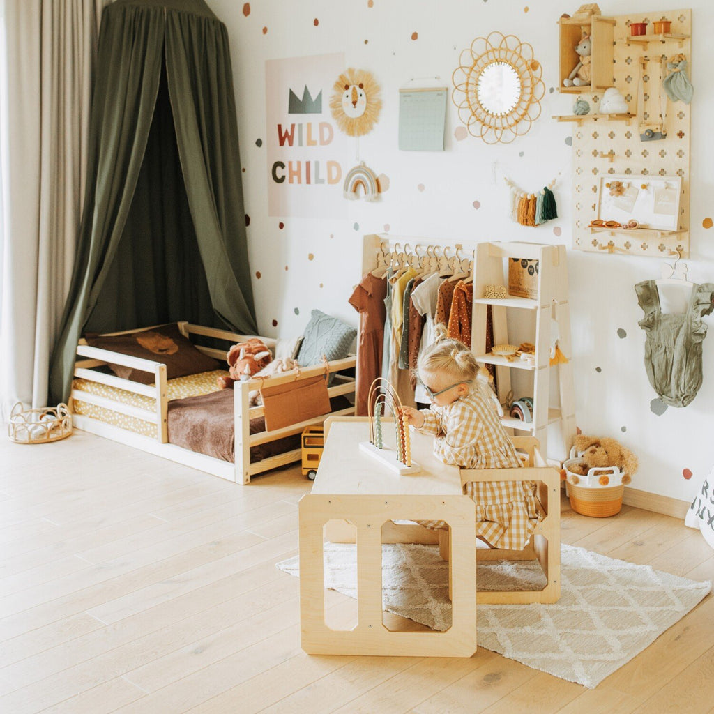 6. Child playing at a natural wood Montessori table and chair set in a cozy, decorated playroom