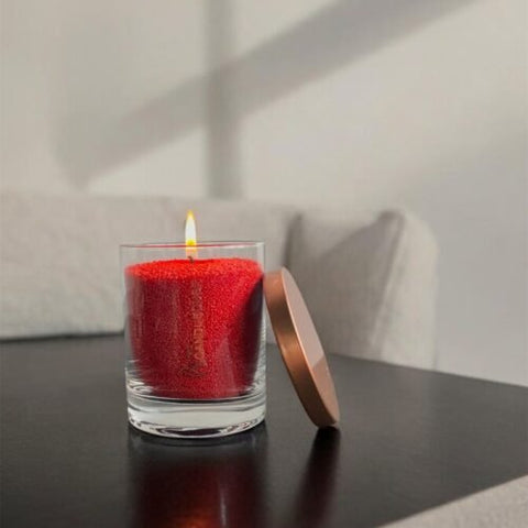 1. Red unscented powder candle by Candledust in glass container with metal lid, burning on a table