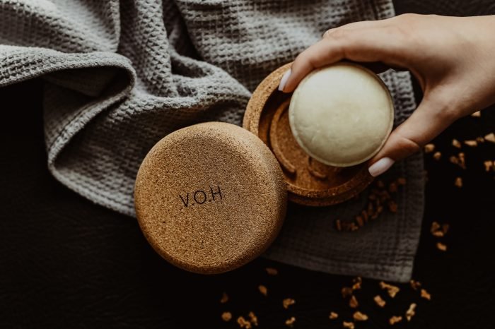8. Hand holding V.O.H solid shampoo with corkwood case, highlighting eco-conscious packaging