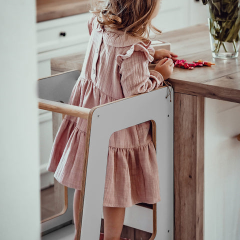 1. Young girl using MeowBaby gray kitchen helper at kitchen counter in cozy home setting