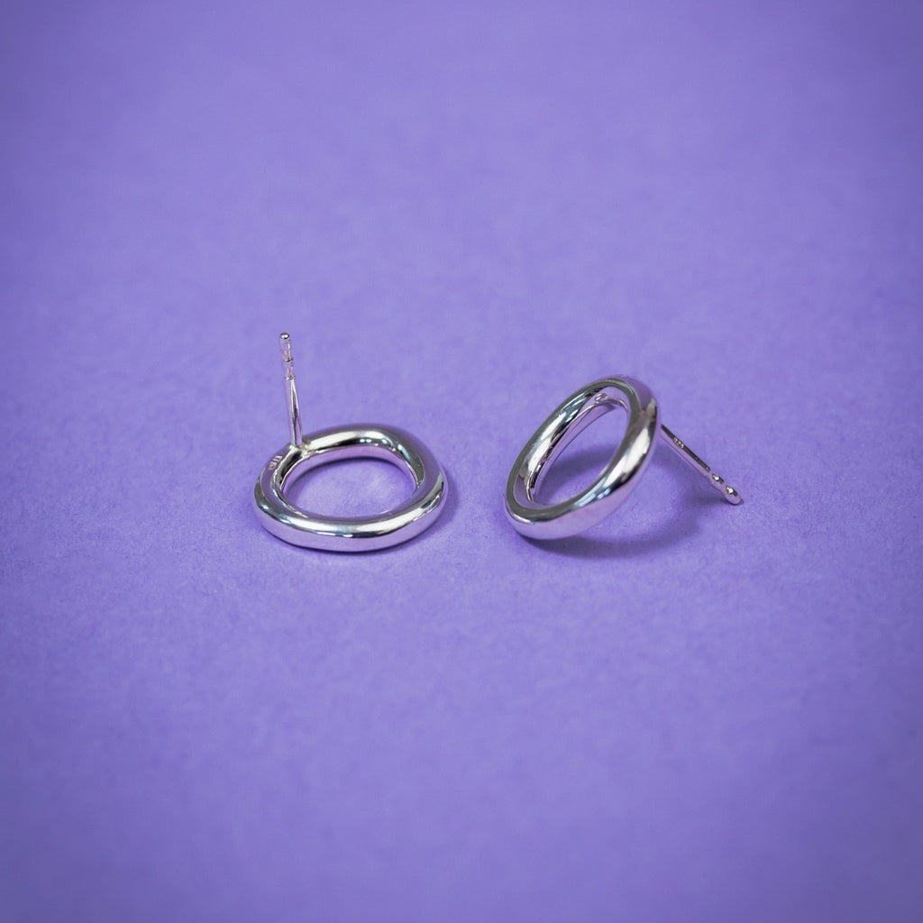 3. Close-up of Maarja Palu Earrings IRREGULAR x1 in polished silver on purple background, highlighting geometric design