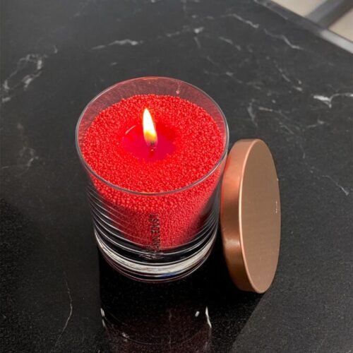 3. Top view of red unscented powder candle by Candledust in glass, burning with lid beside