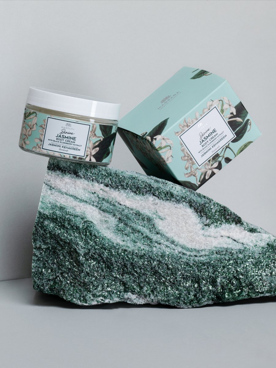 2. Magrada Organic Cosmetics Jasmine Body Cream and box displayed on a textured rock, highlighting elegant packaging