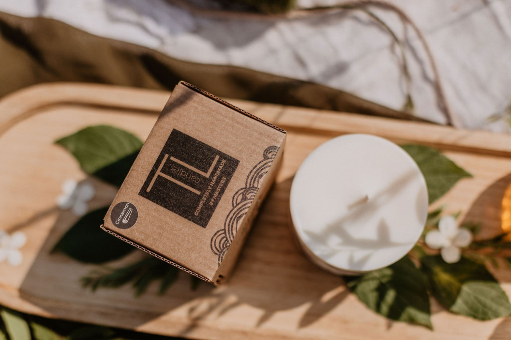 7. Flat lay of TL Candles soy wax candle and packaging on wooden tray with leaves and flowers