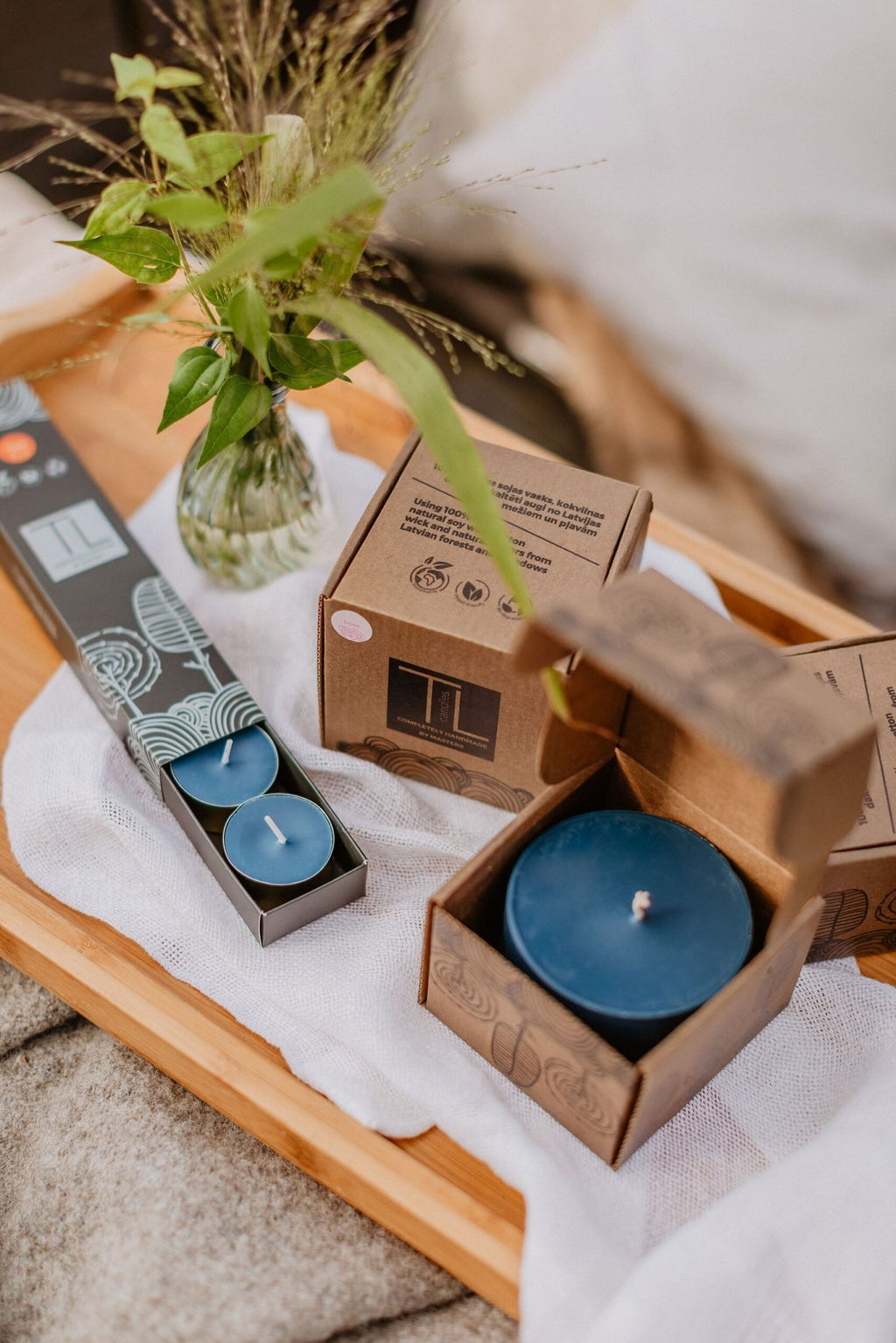 3. TL Candles hand-made blue soy wax candle in open packaging, displayed on a tray with other candles