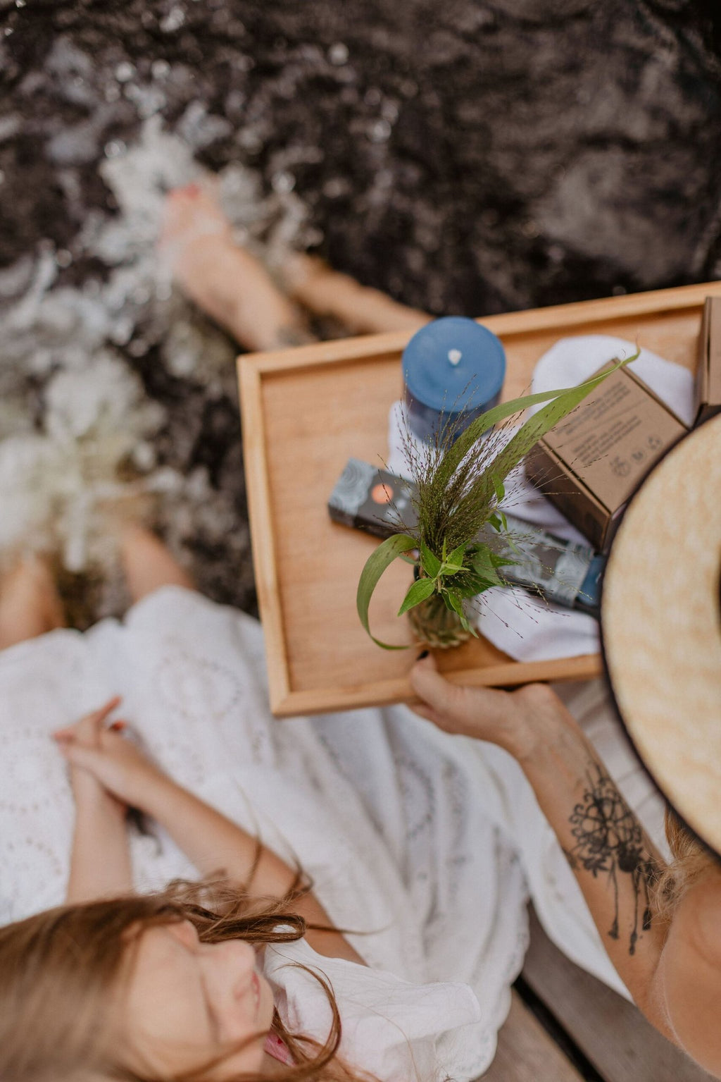 2. Woman holding a tray with TL Candles hand-made blue soy wax candle and other items by the water