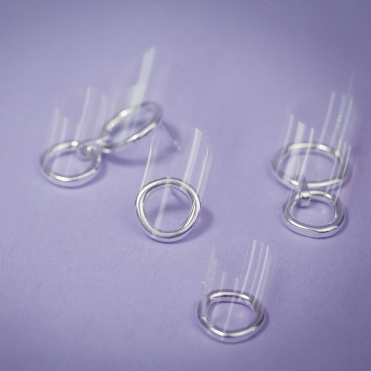 3. Close-up of Maarja Palu IRREGULAR x2 silver earrings with asymmetrical circles on purple background