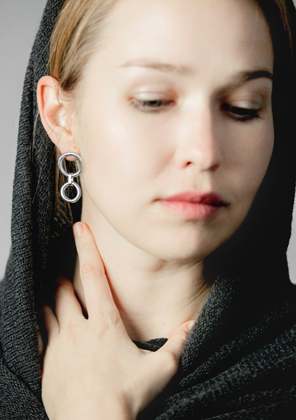 1. Woman wearing Maarja Palu IRREGULAR x2 silver earrings with asymmetrical circles, showcasing modern minimalist design